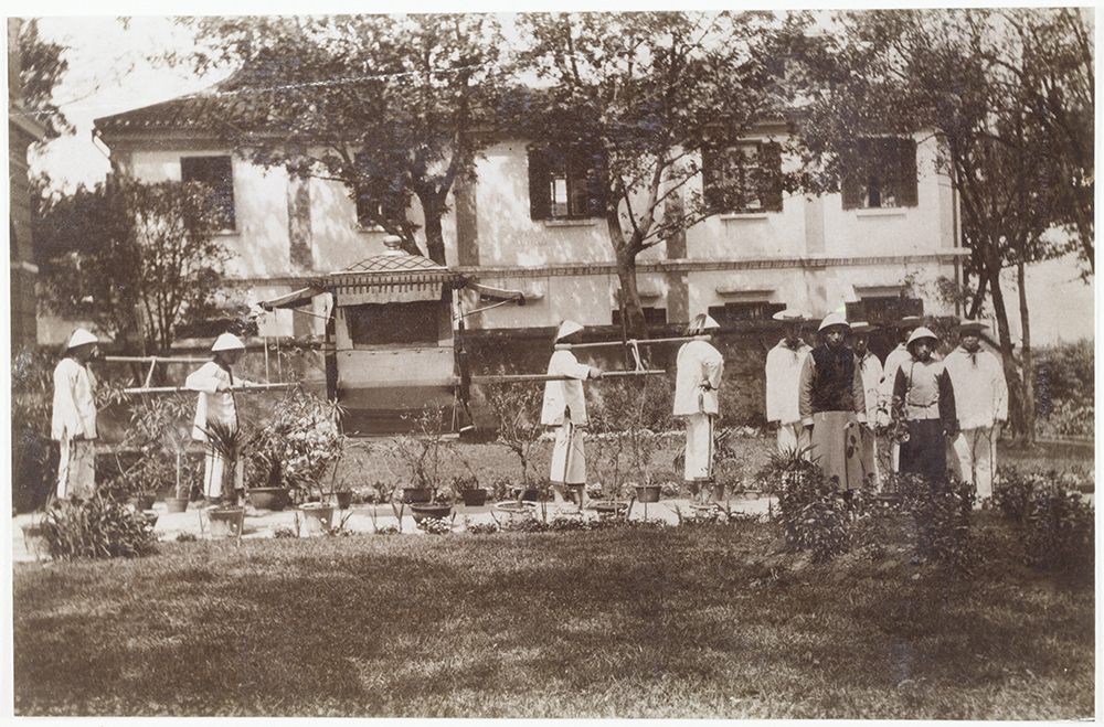 4. Kiukiang, 1904. ‘My official chair and bearers with official servants waiting in the garden for me to go on a round of official calls. The building at the back is the Chinese Post Office of which I am Postmaster’.