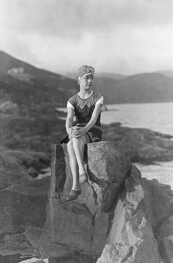 A woman in a swimsuit sitting on a rock. Photograph by Fu Bingchang. Fu Bingchang Collection, Fu-n597 © 2007 C. H. Foo and Y. W. Foo.