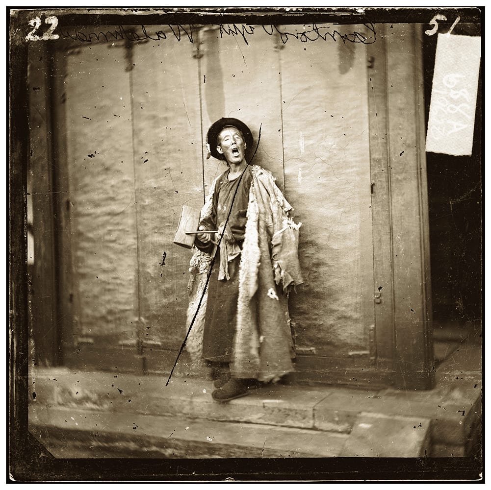 Fig. 6. Listed as ‘one of the city guard, Peking’, the photograph shows a night-watchman with his wooden board, used to sound that all was well: ‘wrapped in his sheep-skin coat and in an under-clothing of rags, he lay through cold nights on the stone steps of the outer gateway and only roused himself to answer the call of his fellow-watchmen near at hand’, Illustrations of China, IV, plate 22. Photograph by John Thomson, negative no. 688a. Credit: Wellcome Collection. CC.BY.