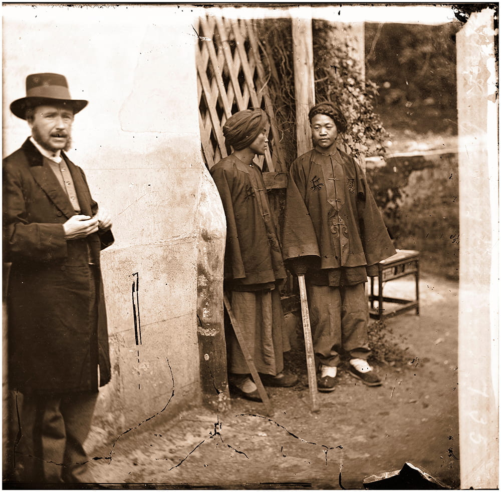 John Thomson, with two soldiers, in Xiamen (Amoy), 1871. Is this the earliest selfie in China? Thomson looks towards his camera, somewhat anxiously, during the exposure. It seems likely that Thomson would have intended to crop off the left-hand side of this image, when the negative was printed or published. A scan of a glass plate negative, numbered 735 by Thomson, held by the Wellcome Collection.
