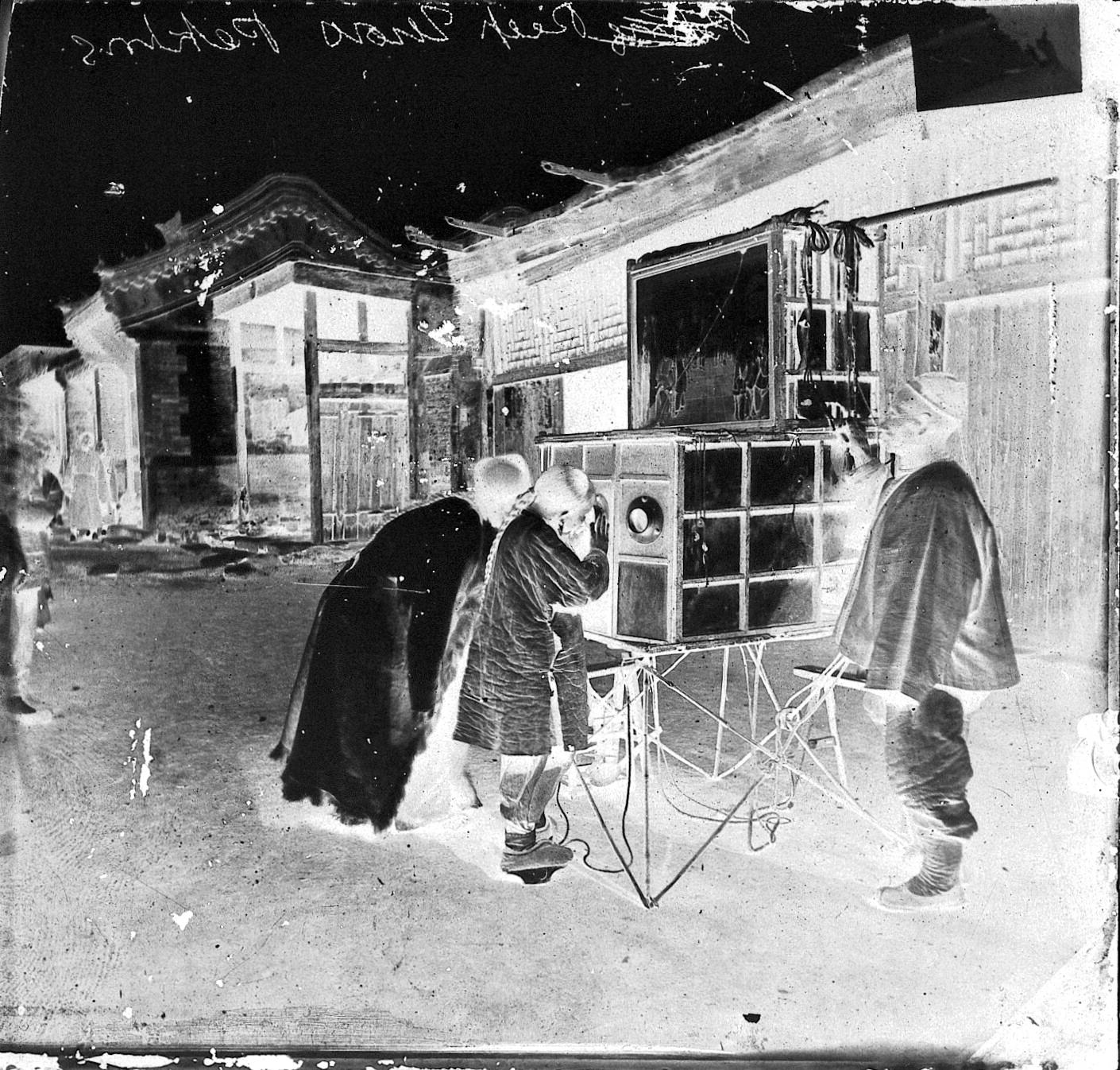 Looking at a peep show in the street, Beijing, c.1870. Photograph by John Thomson. The exhibition prints were made from glass negatives digitised by the Wellcome Collection. Credit: Wellcome Collection. Attribution 4.0 International (CC BY 4.0).